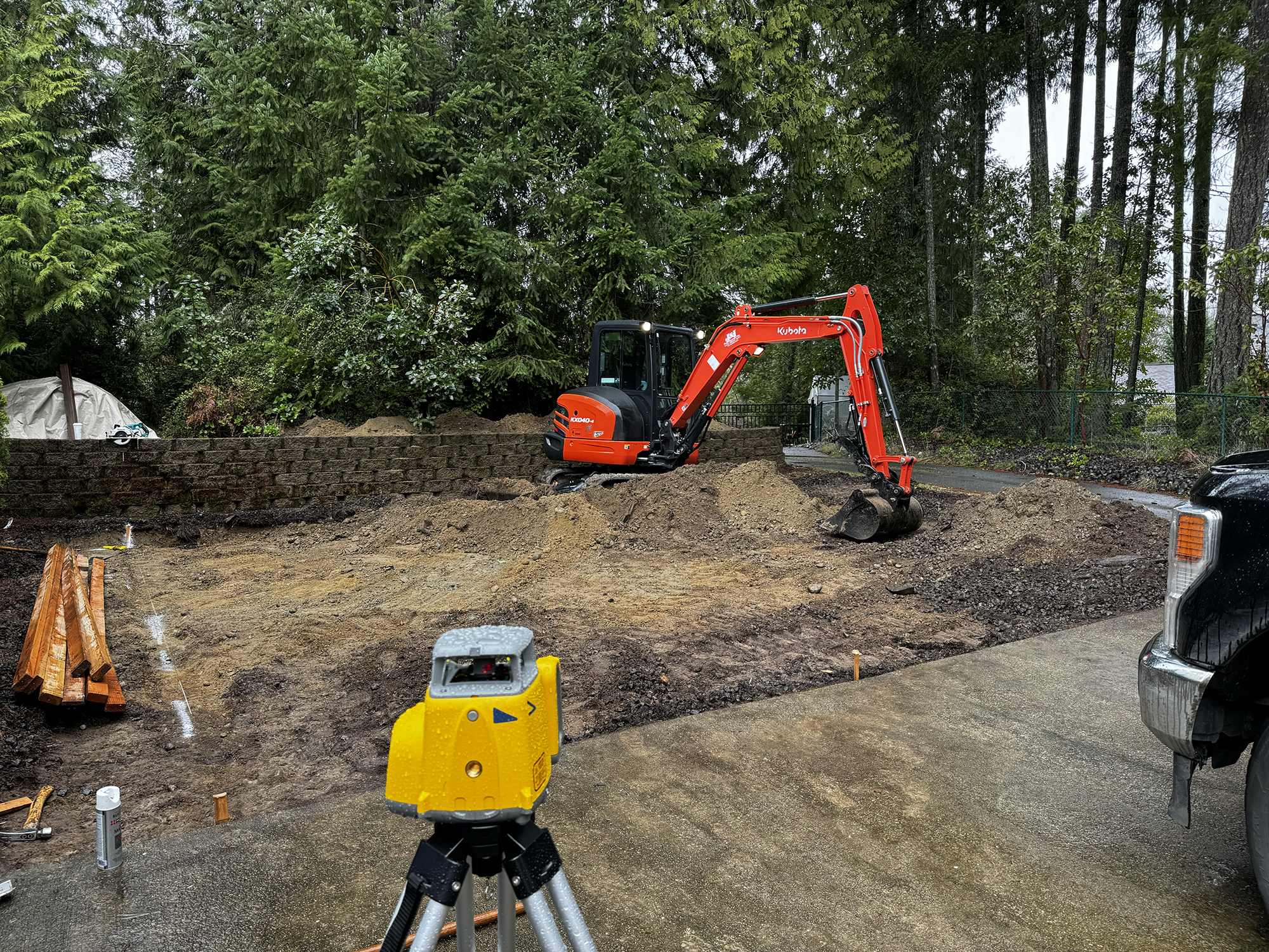 excavator next to retaining wall grading driveway area